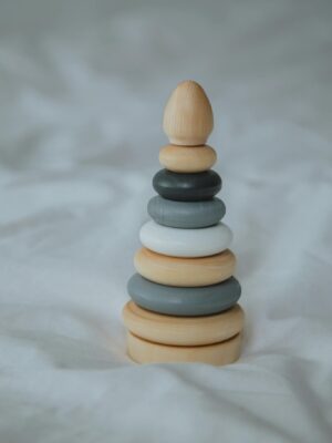 Minimalist photo of a wooden ring stacker toy set against a soft background, ideal for child development themes.